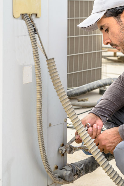 专业电工在屋顶维修重型空调后竖起大拇指，身穿蓝色制服和帽子，城市为背景图片下载