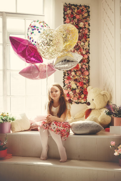 女孩微笑着坐在一个放着气球的房间里图片下载