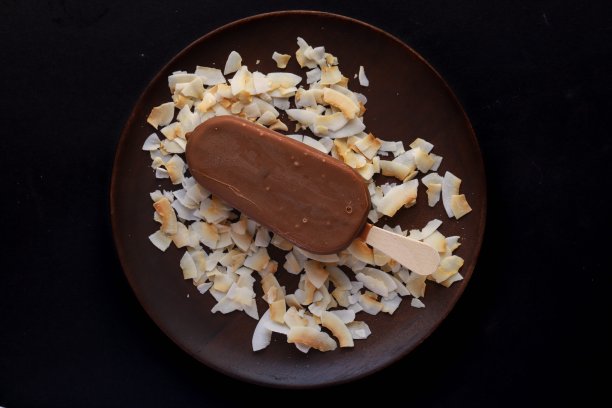 巧克力冰棒放在有椰子屑的木盘上图片下载