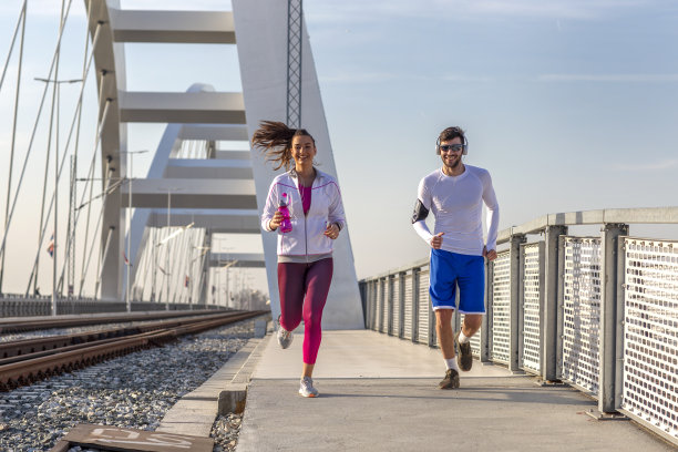 一对情侣在桥边慢跑，戴着耳机听音乐图片下载