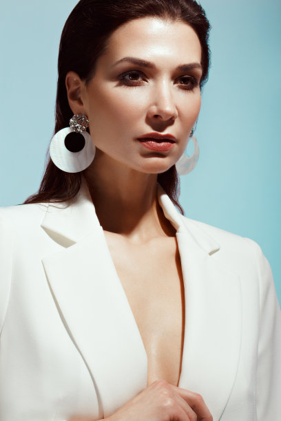 美丽的女孩与经典的化妆和发型在一个时尚的设计师白色夹克摆姿势在工作室。美丽的脸。图片下载