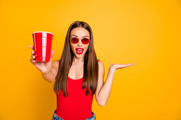 近距离的照片美丽的女士明亮的嘴唇握酒精饮料震惊好品味穿太阳眼镜红色的身体背心牛仔短裤图片下载