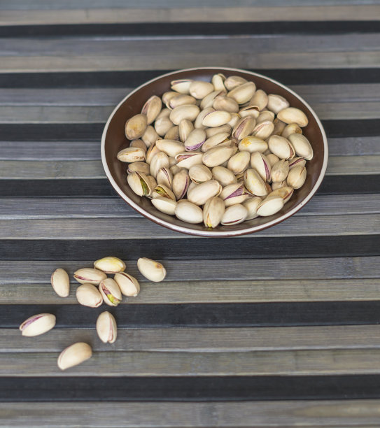 健康的食物背景图片近距离开心果。俯视图果仁开心果在杯盘上图片下载