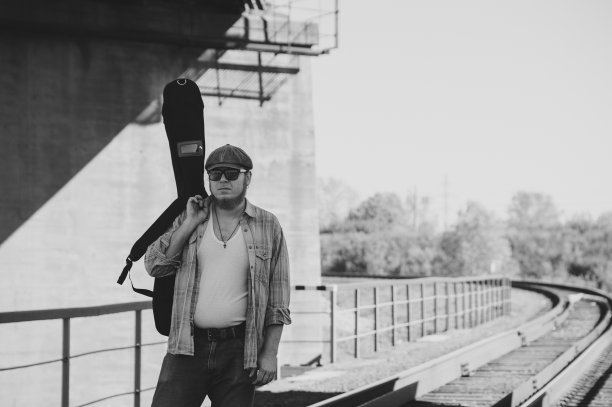 带着吉他盒的蓝调歌手走在铁路上。铁路上的蓝调音乐家。有吉他的酷小伙。有胡子的人轻装出行。流浪的嬉皮士生活方式。穿单色衣服的怪人。图片下载