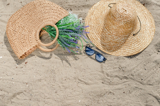 戴着草帽和包的太阳镜躺在沙滩上。暑假的场景图片下载