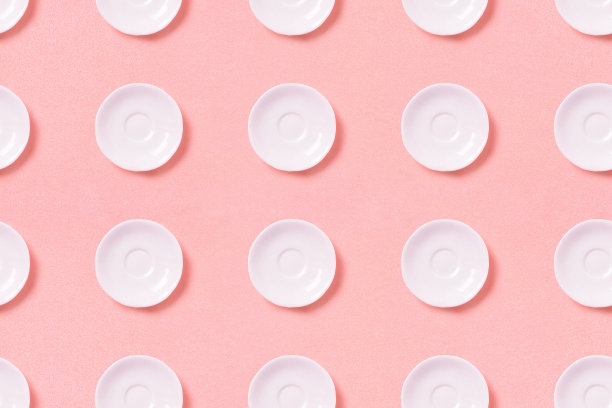 粉红色背景上的白色小盘子的集合。模式俯视图图片下载