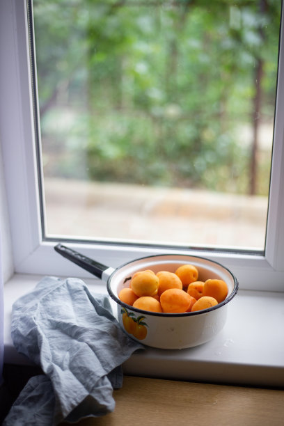 靠窗的旧搪瓷锅里放着新鲜多汁的杏子。夏天的概念图片下载