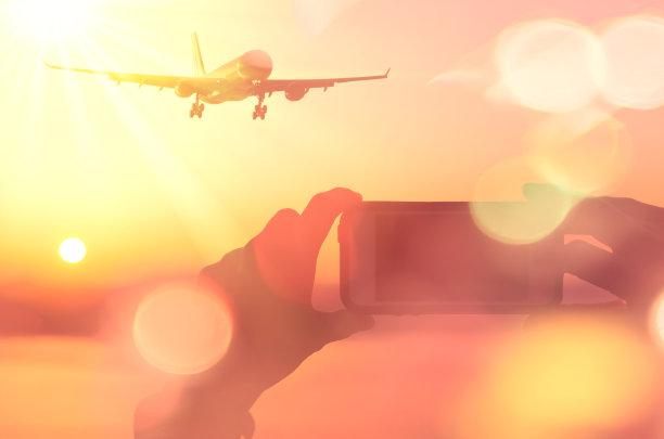 女人手拍照片飞机飞过日落海滩双曝光彩色散景光抽象背景。商务交通和暑期旅游冒险理念。复古风格图片下载