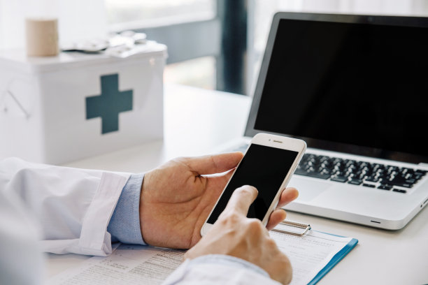 医生使用移动智能手机和笔记本电脑在病房的桌子上，远程医疗或视频会议，图片下载