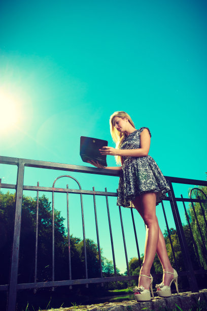 女人坐在公园里，放松和使用平板电脑图片下载