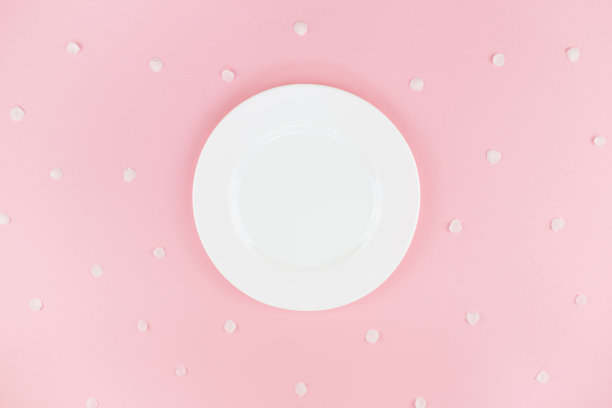 白色的盘子在粉红色的背景和白色的花瓣。图片下载
