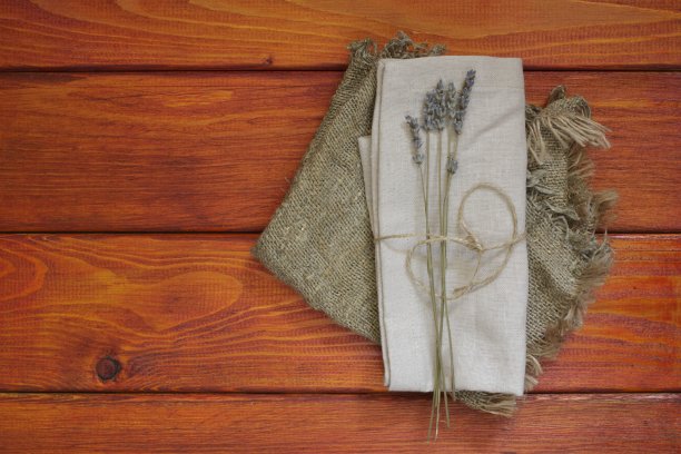 亚麻餐巾在木板上，厨房米色餐巾，绳子，薰衣草花在红色的背景，沙色餐巾从天然织物为厨房，俯视图图片下载