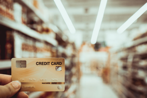 手握信用卡模糊超市，购物和零售的概念图片下载