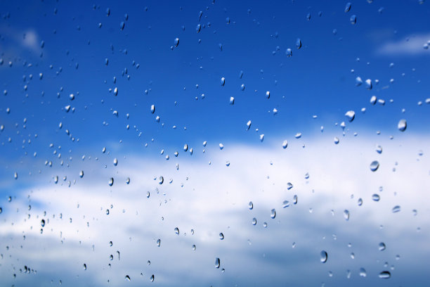 雨滴落在窗户上，清澈的蓝天背景图片下载
