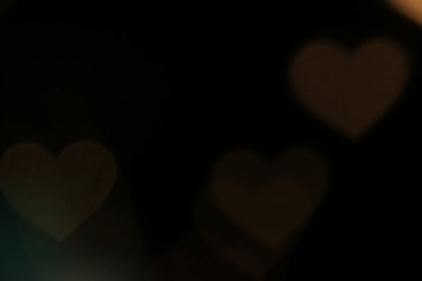 彩色心形灯饰以黑色背景为背景，以散景为装饰背景墙纸模糊情人节，爱情图片背景，心形灯饰在夜晚柔和抽象图片下载