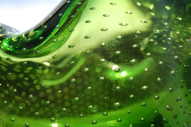 这是一碗绿色玻璃的极端特写，里面有气泡和后面的天空。图片下载