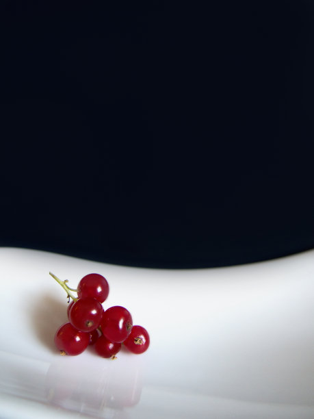 红色的醋栗浆果在白色弯曲的盘子上在黑暗的背景图片下载