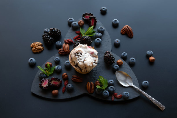 在黑色背景上的新鲜水果，浆果和坚果，在华夫杯里的静止生活的冰淇淋。照片蓝莓，蓝莓，坚果。用新鲜薄荷装饰。俯视图，平放。图片下载