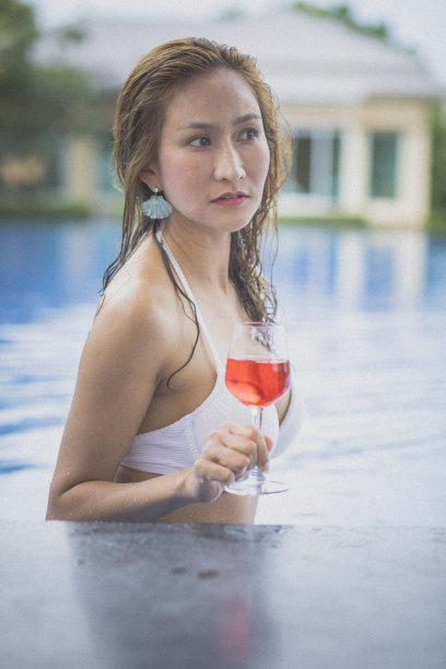 比基尼女郎和一杯红色饮料在游泳池里图片下载