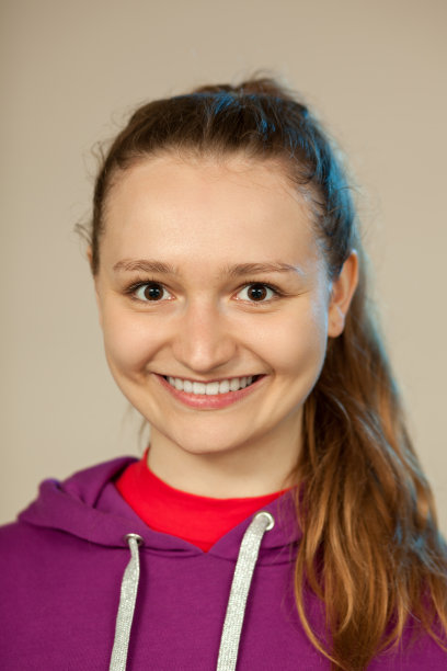 一个迷人的18岁女人在米色背景的工作室肖像图片下载