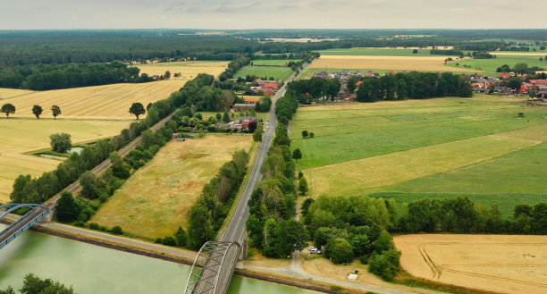 鸟瞰图的一个德国小村庄在德国北部的平坦地区有牧场，耕地和奶牛，乡村公路和铁路在一边图片下载