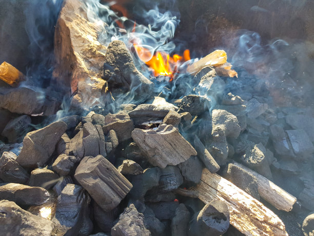 煤块在余烬上产生的烟。为烧烤余烬准备火。户外娱乐。图片中可以看到火焰。图片下载
