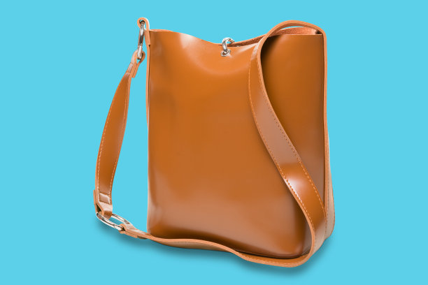 皮革棕色女性手提包与一个长柄，在绿松石的背景图片下载