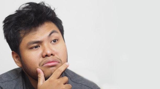 一个困惑的年轻亚洲男子在白色背景和拷贝空间。图片下载