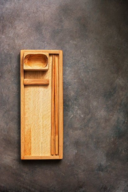 一套木制的盘子和餐具亚洲食物寿司和卷，一个长方形的盘子，筷子和一个盛酱油的碗在黑暗的背景上。俯视图，平放，复制空间。图片下载