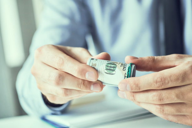 手里拿着一排美元钞票的男子。货币信贷的概念。健美的图片。图片下载