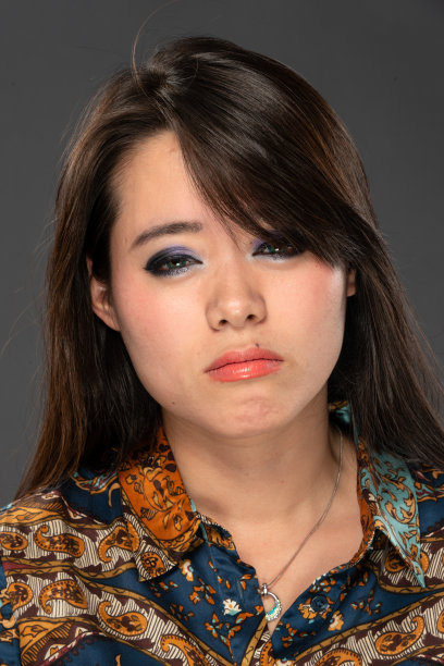 亚洲妇女摆姿势看着相机在灰色的背景图片下载