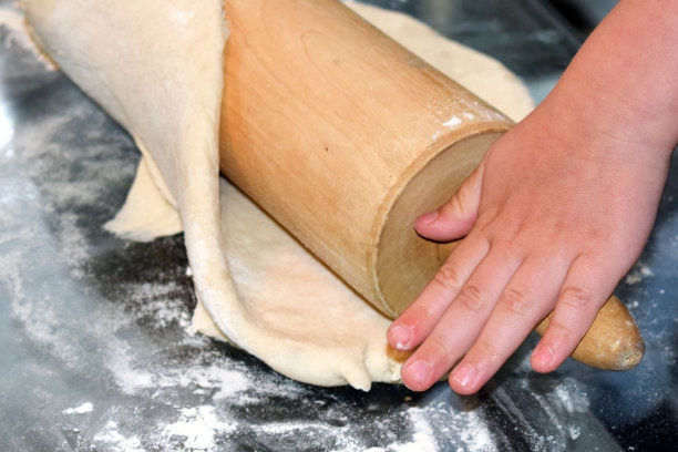 这个女孩在厨房的桌子上揉面团。图片下载