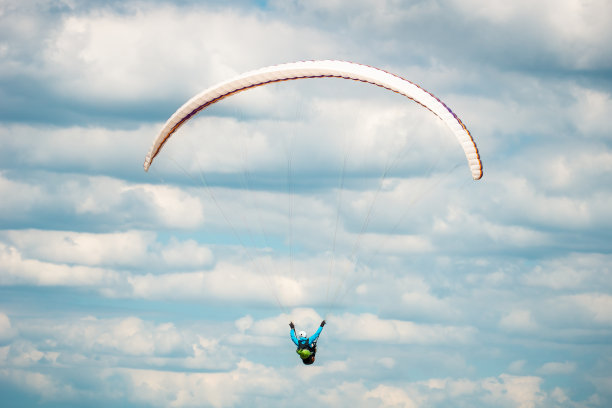 在多云的蓝色天空中飞行的滑翔伞的背面或后视图。图片下载