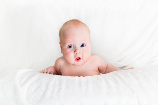 四个月大的婴儿从白色的表面往外看图片下载