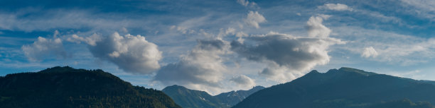 全景的山景观覆盖在郁郁葱葱的绿色森林下的天空和云彩景观图片下载