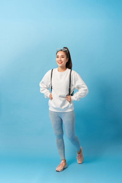 全长照片的亚洲女学生行走与背包孤立在浅蓝色的背景图片下载