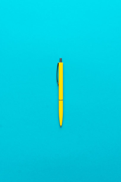 极简主义平铺照片的黄色圆珠笔在蓝绿色的背景图片下载
