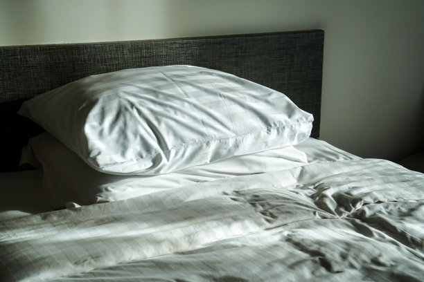 酒店房间里凌乱的床、床单和枕头图片下载