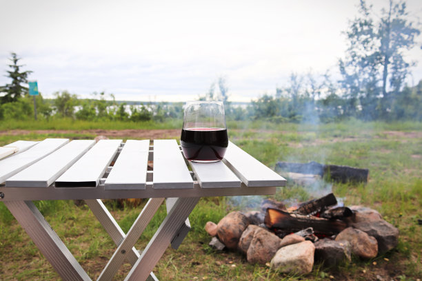 图片的一个葡萄酒杯与一个湖和篝火在背景图片下载