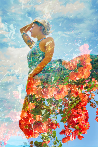 一张自然美景的双曝光照片，她穿着飘逸的裙子，配上葱郁的橙色花朵和蔚蓝的天空图片下载