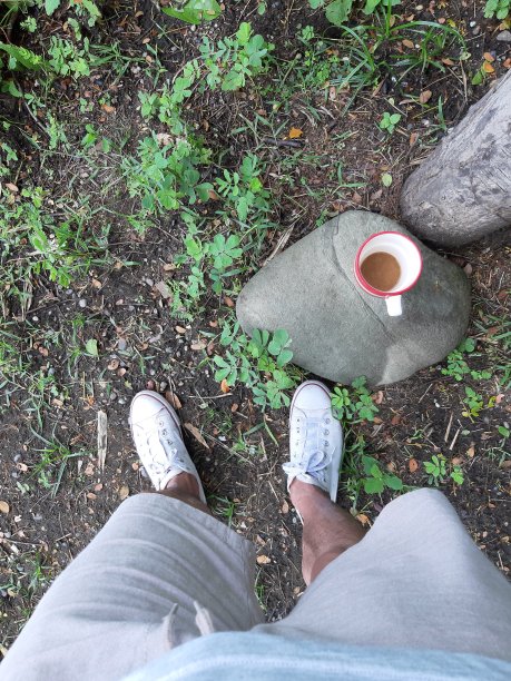 悠闲地喝着咖啡，杯子放在一块石头上图片下载