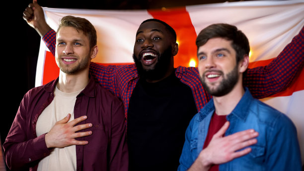 白人和黑人男性朋友唱着国歌，挥舞着英国国旗图片下载