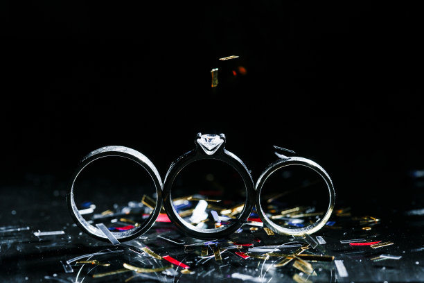 彩色照片与散景美丽的三枚婚戒钻石箔纸屑落在黑色的背景图片下载