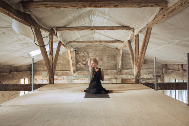 一名年轻女子在一个废弃的建筑工地练习瑜伽图片下载