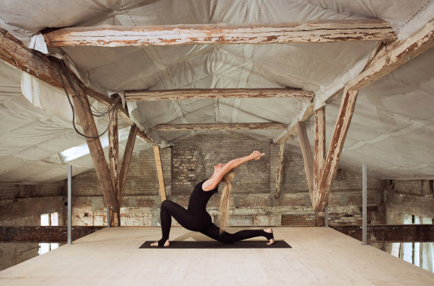一名年轻女子在一个废弃的建筑工地练习瑜伽图片下载
