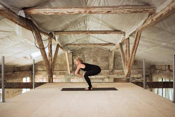 一名年轻女子在一个废弃的建筑工地练习瑜伽图片下载