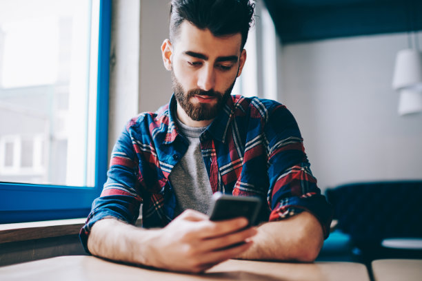 年轻潮男在校园里通过智能手机上的应用程序进行交易，千禧男用手机在室内通过无线网络在社交网络上阅读新闻图片下载