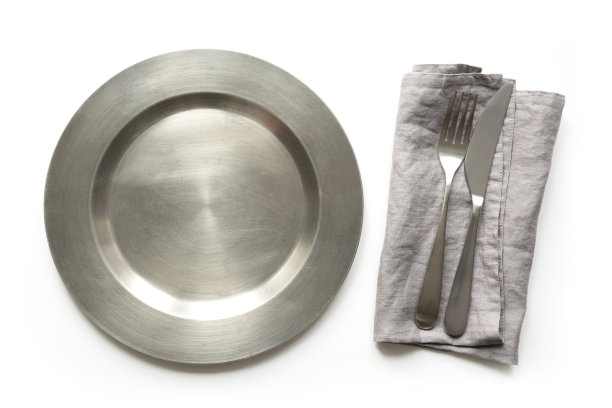 白色的桌子上放着空的金属盘子和刀叉。表设置。图片下载