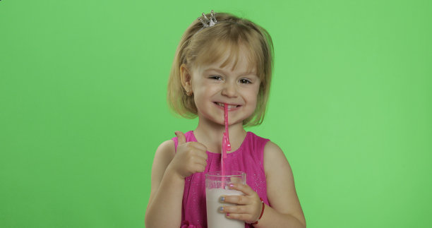 快乐的四岁小孩在粉红色的裙子喝奶昔鸡尾酒。竖起大拇指图片下载
