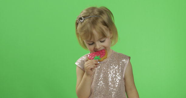 穿着光鲜的裙子的女孩开始吃草莓形状的饼干图片下载